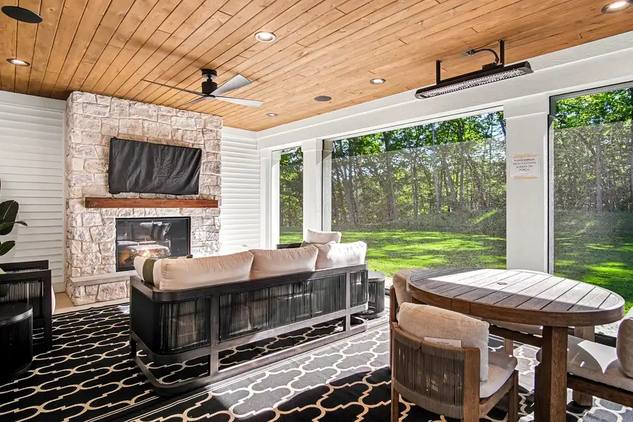 A high-end kitchen addition featuring rich walnut flat-panel cabinetry with brushed gold hardware, a bold emerald green herringbone tile backsplash behind a professional-grade gas range, and a geometric black-and-white hex tile floor visible through the doorway. A striking Philadelphia home addition combining luxury finishes with modern design.