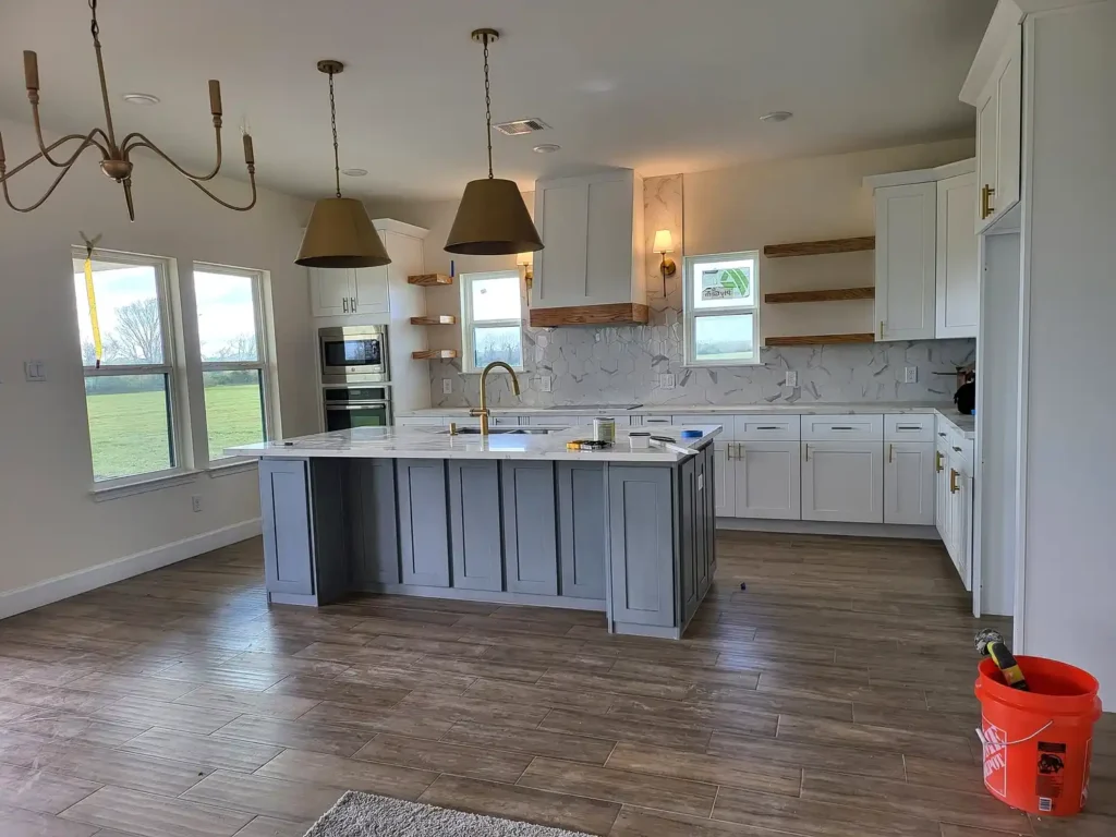 This bold kitchen remodel showcases dramatic black cabinetry paired with granite countertops, a farmhouse apron sink, and a grey stone mosaic backsplash. Under-cabinet lighting highlights the rich contrast between the dark cabinets and light countertops, while stainless steel appliances add a modern touch. A striking kitchen renovation choice for Philadelphia homes seeking a high-contrast, contemporary look.