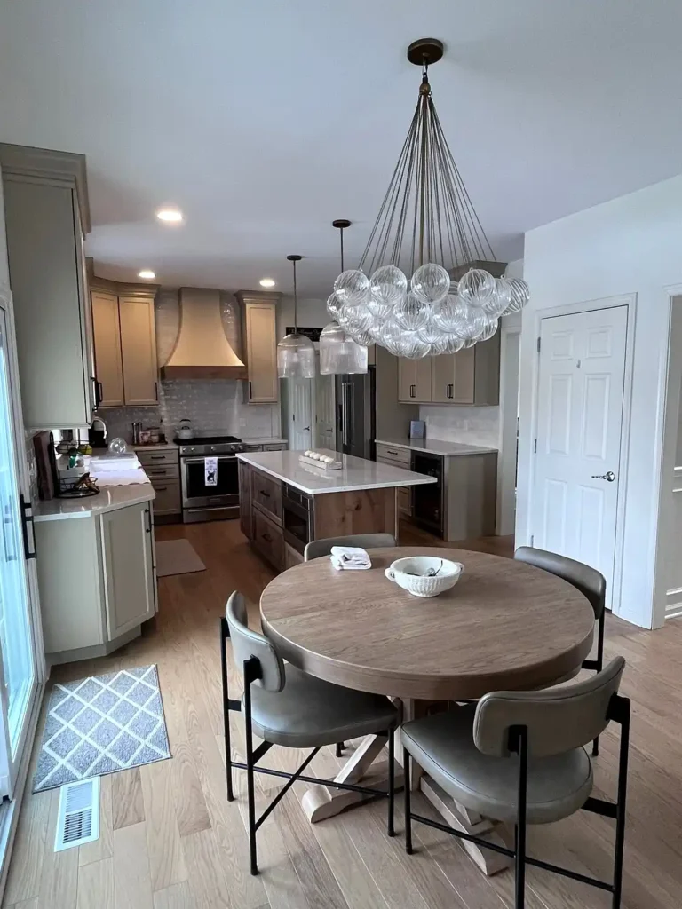 This bold kitchen remodel showcases dramatic black cabinetry paired with granite countertops, a farmhouse apron sink, and a grey stone mosaic backsplash. Under-cabinet lighting highlights the rich contrast between the dark cabinets and light countertops, while stainless steel appliances add a modern touch. A striking kitchen renovation choice for Philadelphia homes seeking a high-contrast, contemporary look.